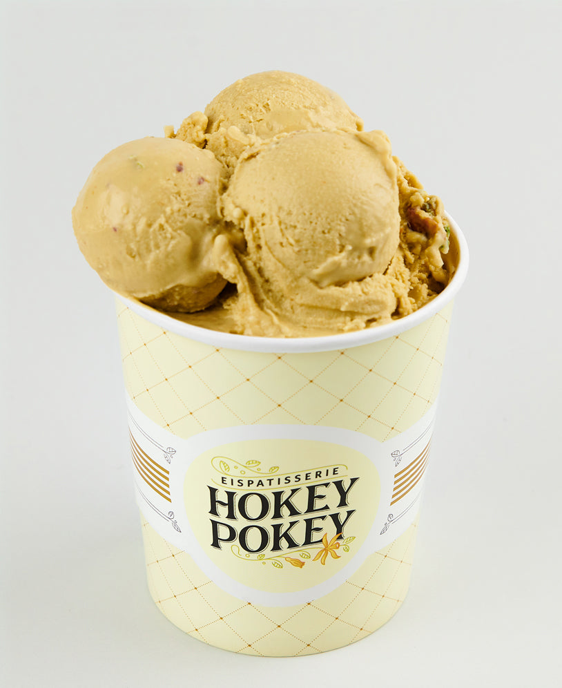 Becher mit Pistazieneis der Eispatisserie Hokey Pokey Berlin, serviert in markantem Designbecher mit Logo – cremig, handgemacht und hochwertig fotografiert vor hellem Hintergrund.