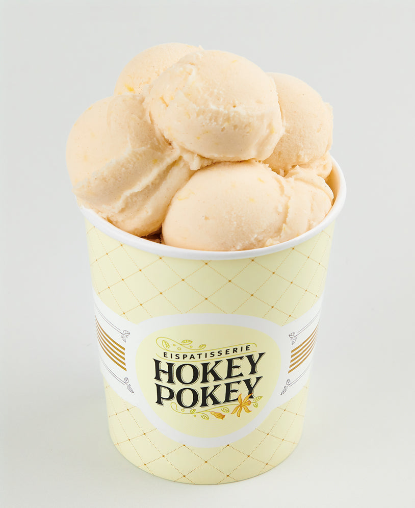 Becher mit cremigem Zimt-Zitronen-Eis von Hokey Pokey, serviert mit mehreren Kugeln in zartem Pastellgelb – dekorativ angerichtet in einem stilvoll gebrandeten Eisbecher.