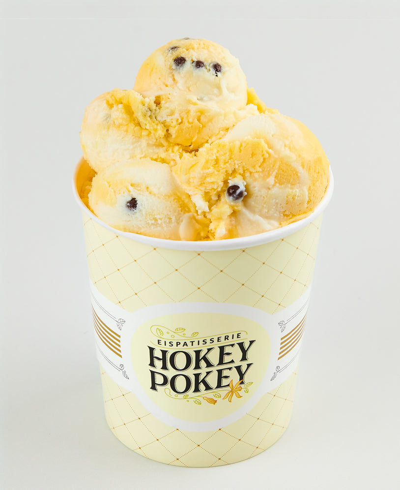 Becher der Eispatisserie Hokey Pokey gefüllt mit cremigem Passionsfrucht- und weißem Schokoladeneis, verfeinert mit dunklen Schoko-Perlen.